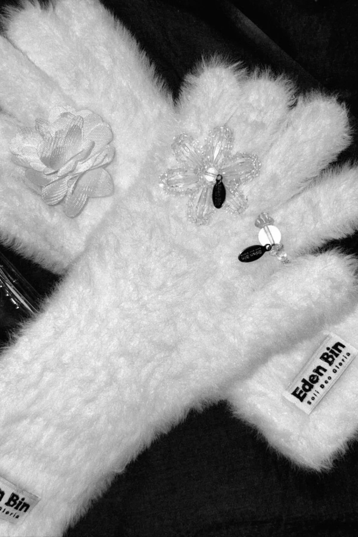 White fluffy gloves with floral bead embellishments and Eden Bin brand labels on black background