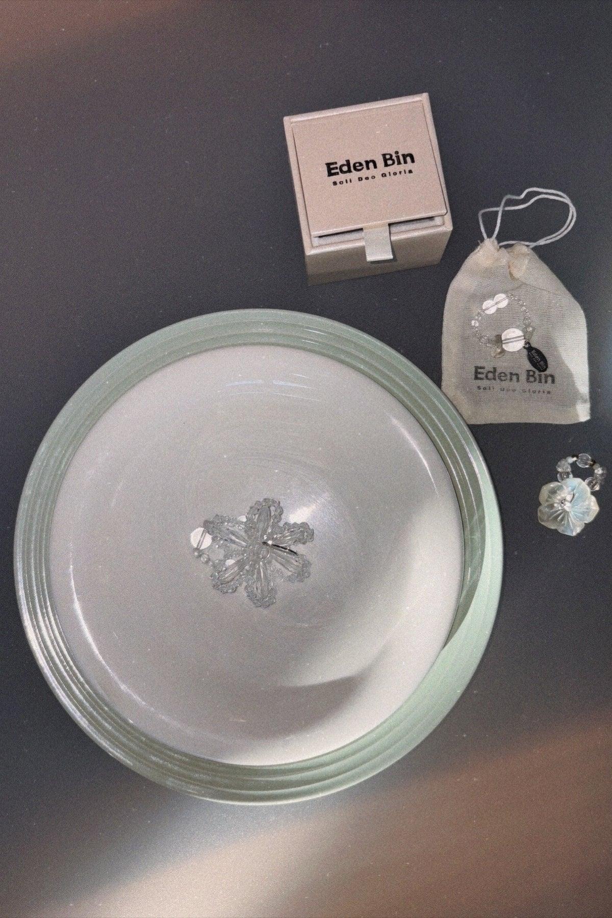 Clear beaded flower ring on ceramic plate with Eden Bin jewelry box and pouch on gray surface