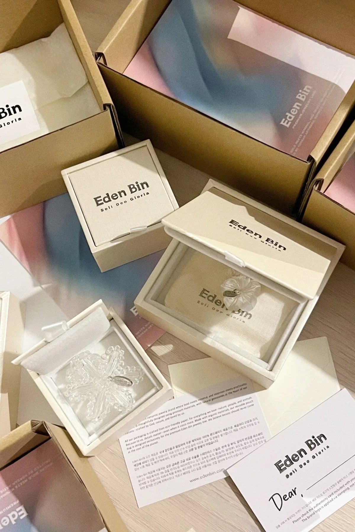 Eden Bin jewelry packaging with open white ring boxes displaying crystal-like rings and branded cards