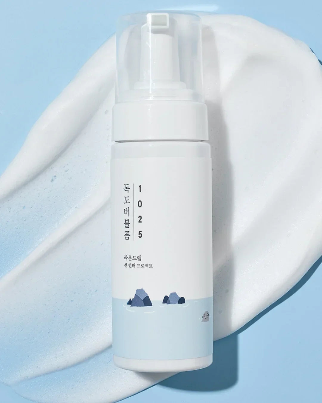 White bottle of Dokdo Bubble Foam cleanser with light blue sea graphic on white foam background