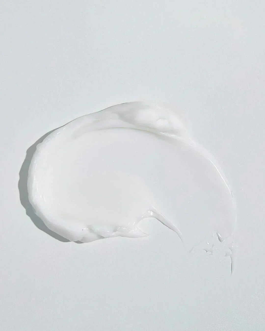 Close-up of smooth white Dokdo cream texture on a plain white background