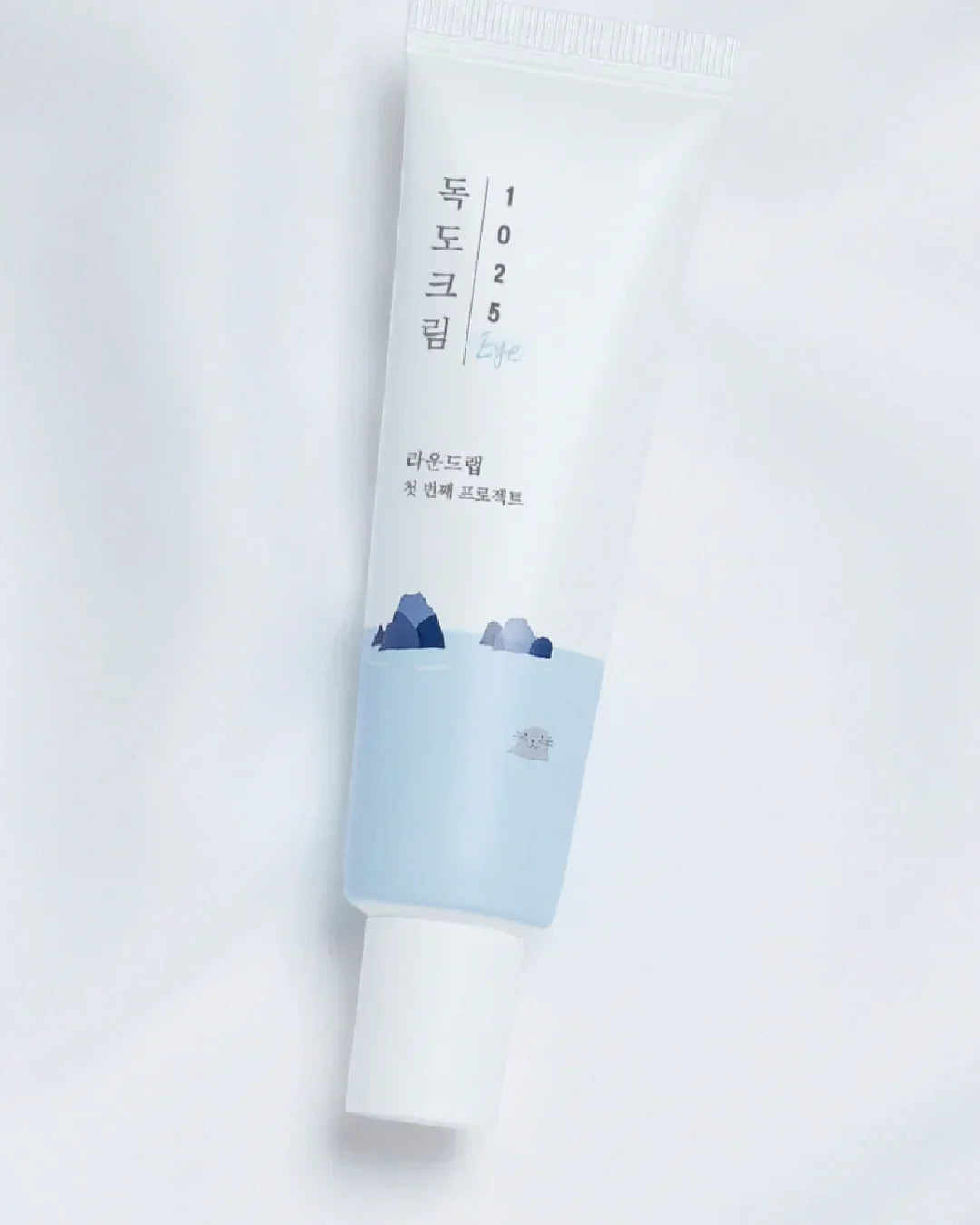 Dokdo 1025 Eye Cream tube with blue mountain and water design on white background