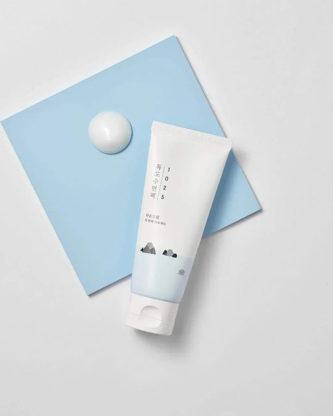 1025 Dokdo Sleeping Pack tube on blue board with cream texture dollop on white background