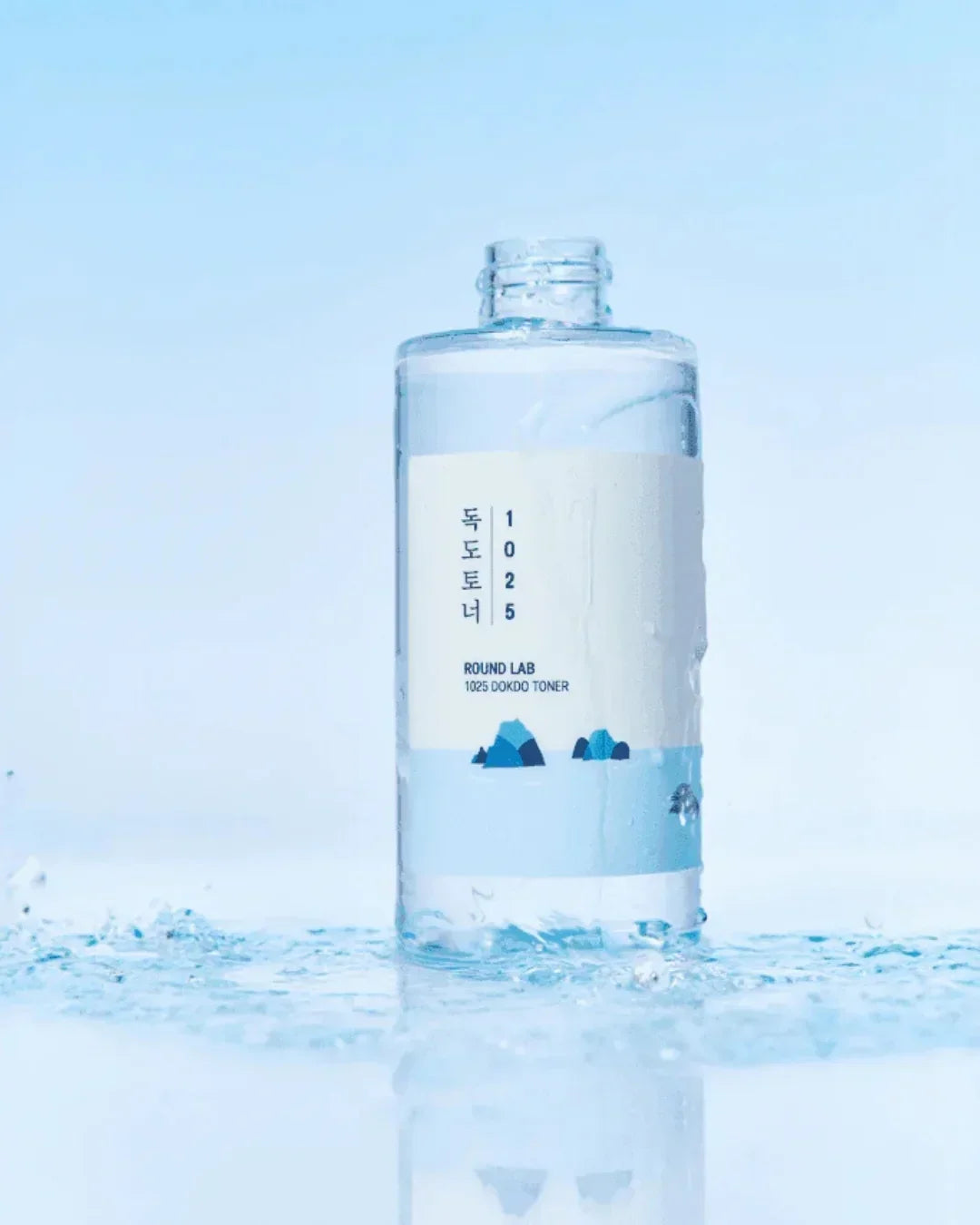 Round Lab 1025 Dokdo Toner bottle on water surface with splashes and light blue background