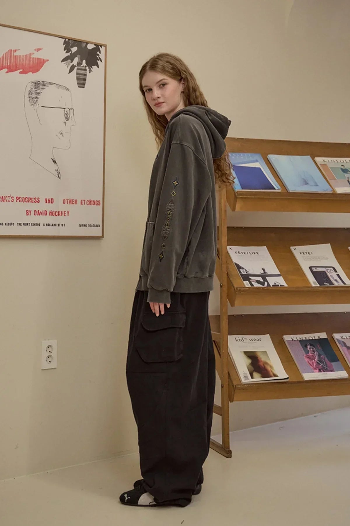 Young woman wearing smoke black hooded zip-up oversized hoodie and wide cargo pants indoors