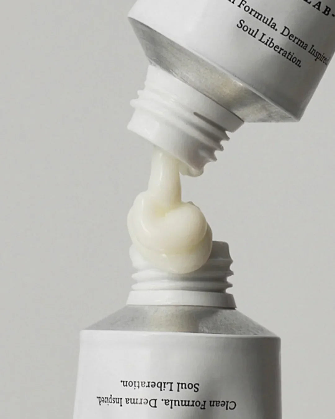 White relief cream being squeezed from one tube to another against a plain background
