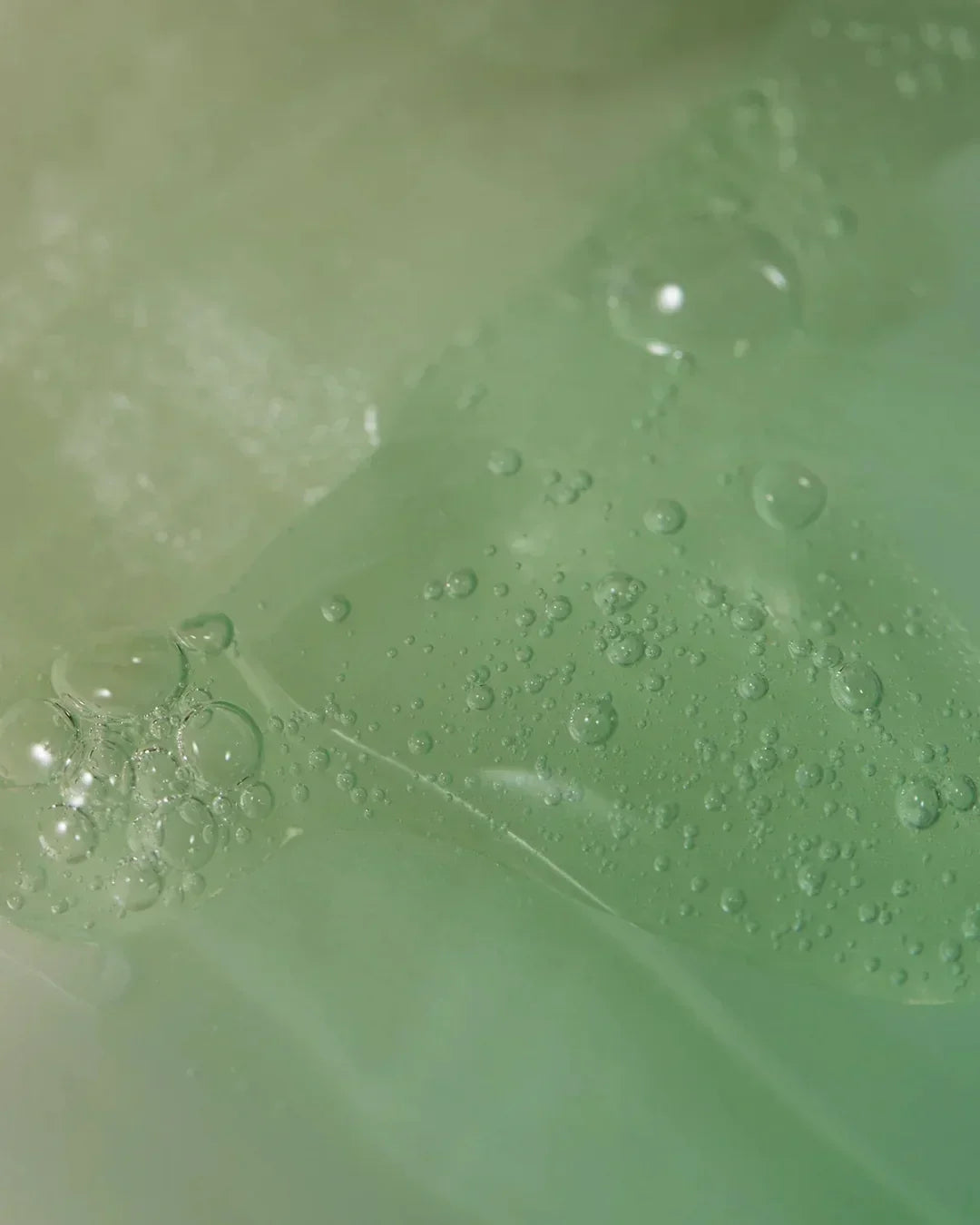 Close-up of translucent green gel with bubbles, showcasing skincare product texture