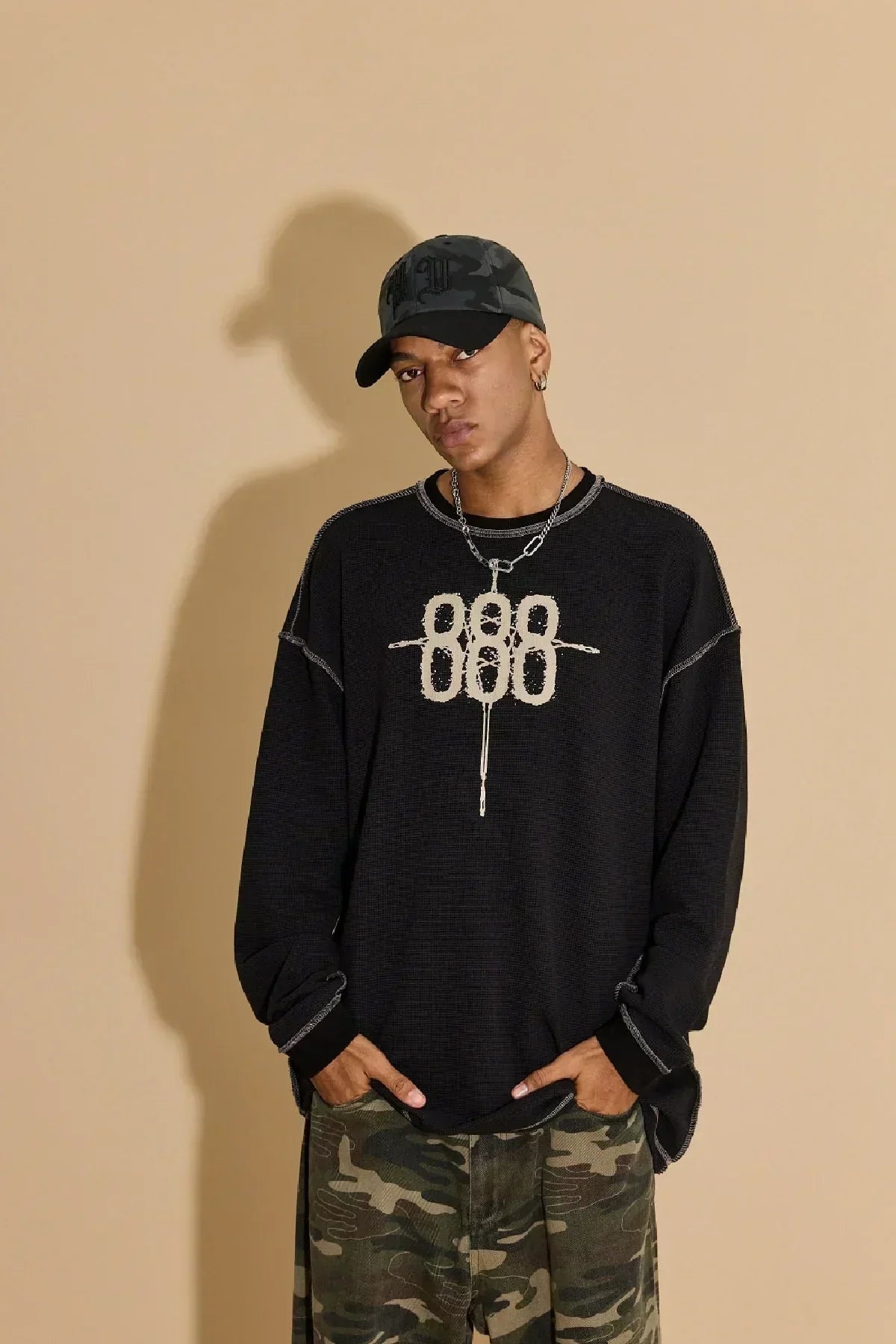 Male model wearing black 888 waffle long sleeve t-shirt and camouflage pants with black cap