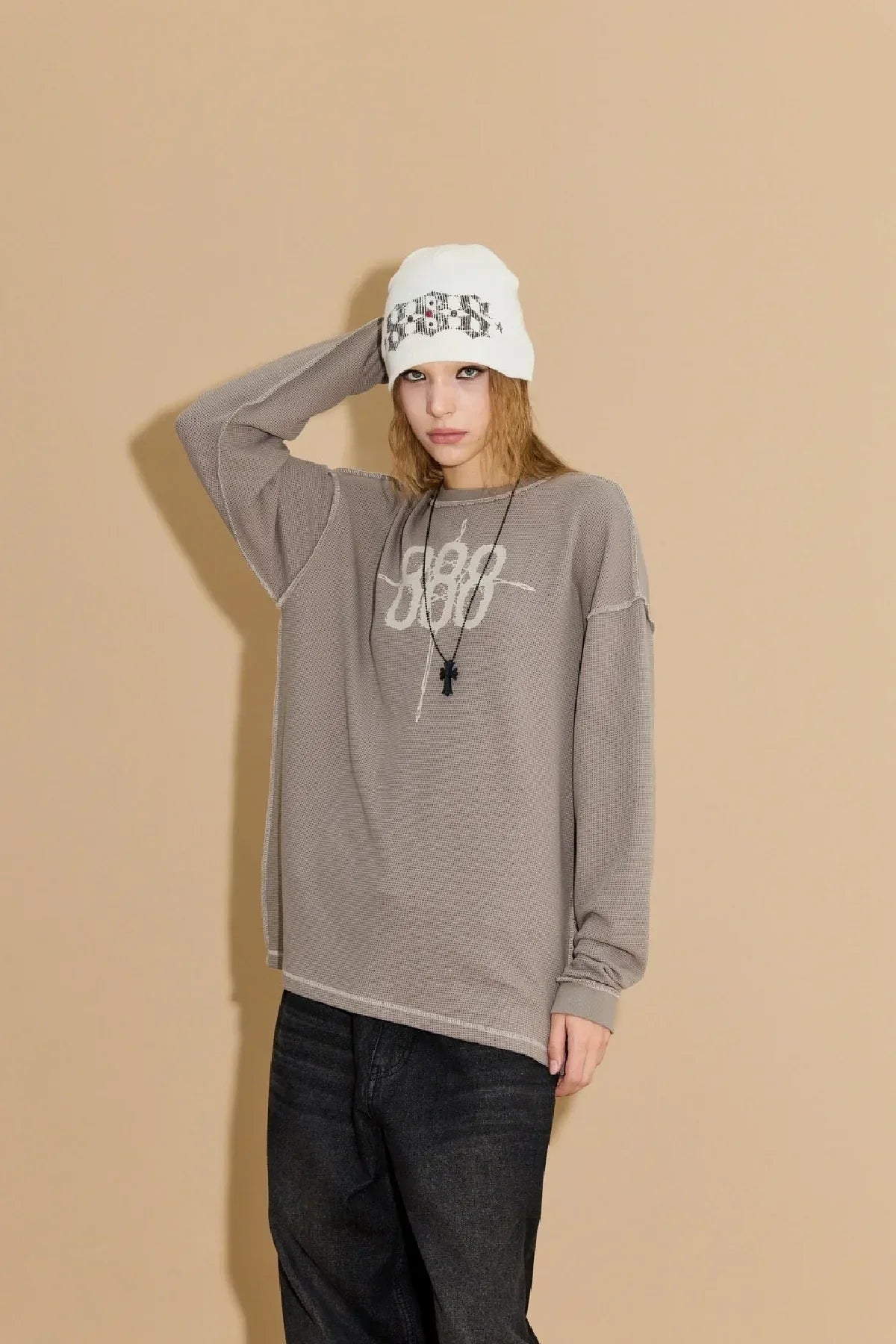 Model wearing greyish beige waffle long sleeve t-shirt with White beanie and black necklace