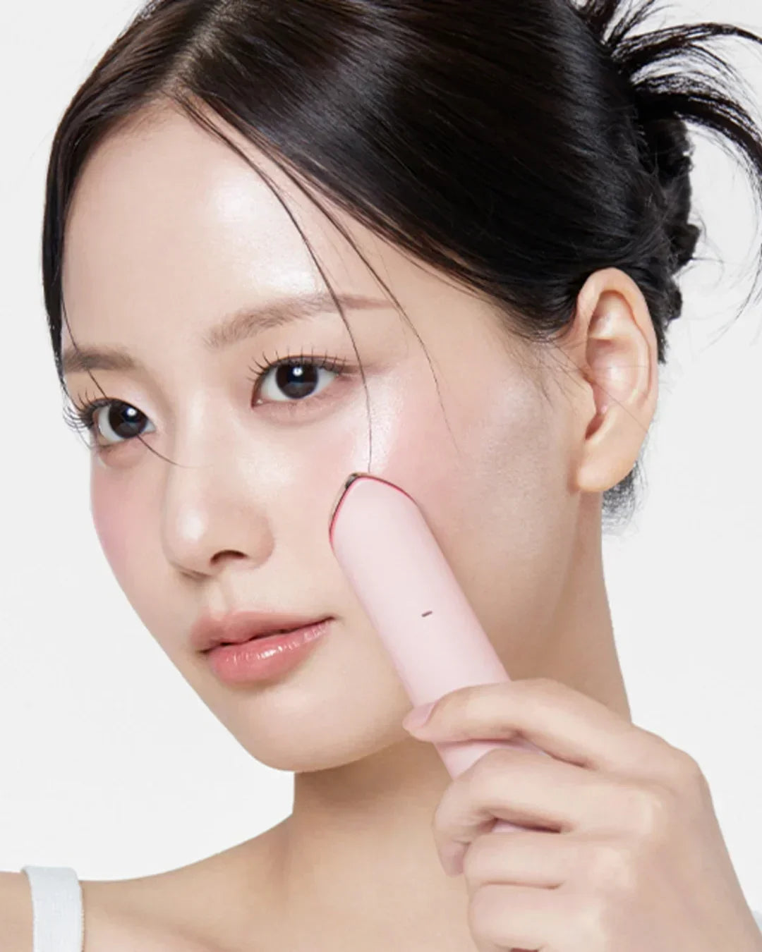 Woman using pink Korean beauty facial device on cheek, clear skin, Malkn UK lifestyle platform