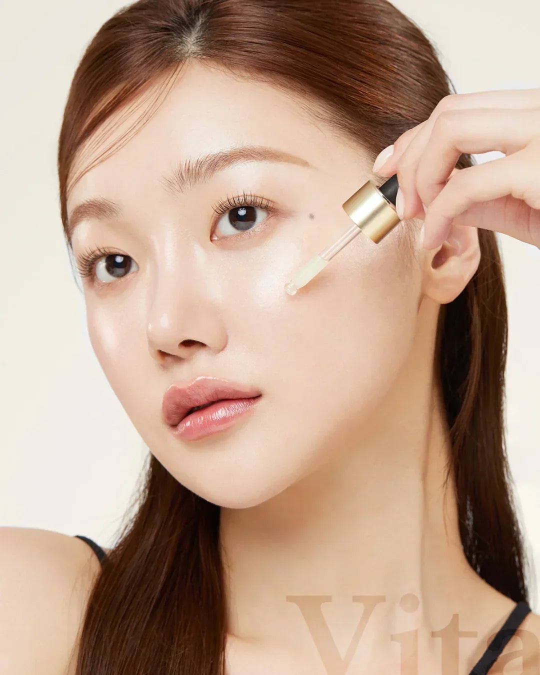 Woman applying Age R Vita C Pro Ampoule serum with dropper to her glowing facial skin