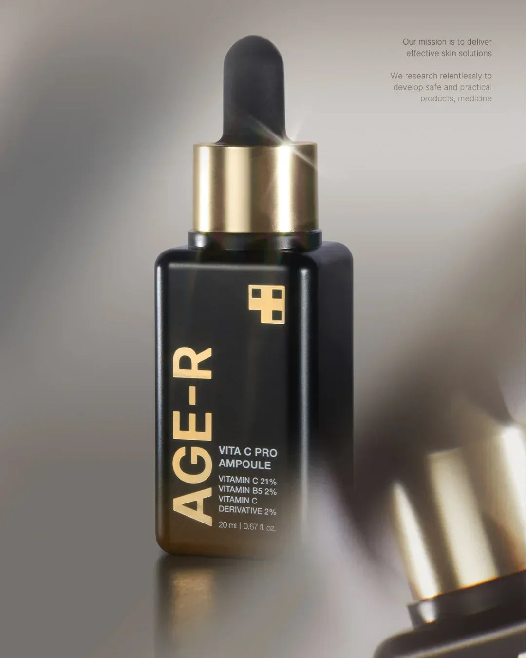 Black glass bottle of Age-R Vita C Pro Ampoule with gold dropper cap on gray background