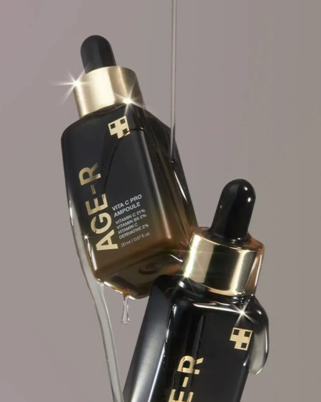 AGE-R Vita C Pro Ampoule bottles with black droppers and gold accents, serum dripping