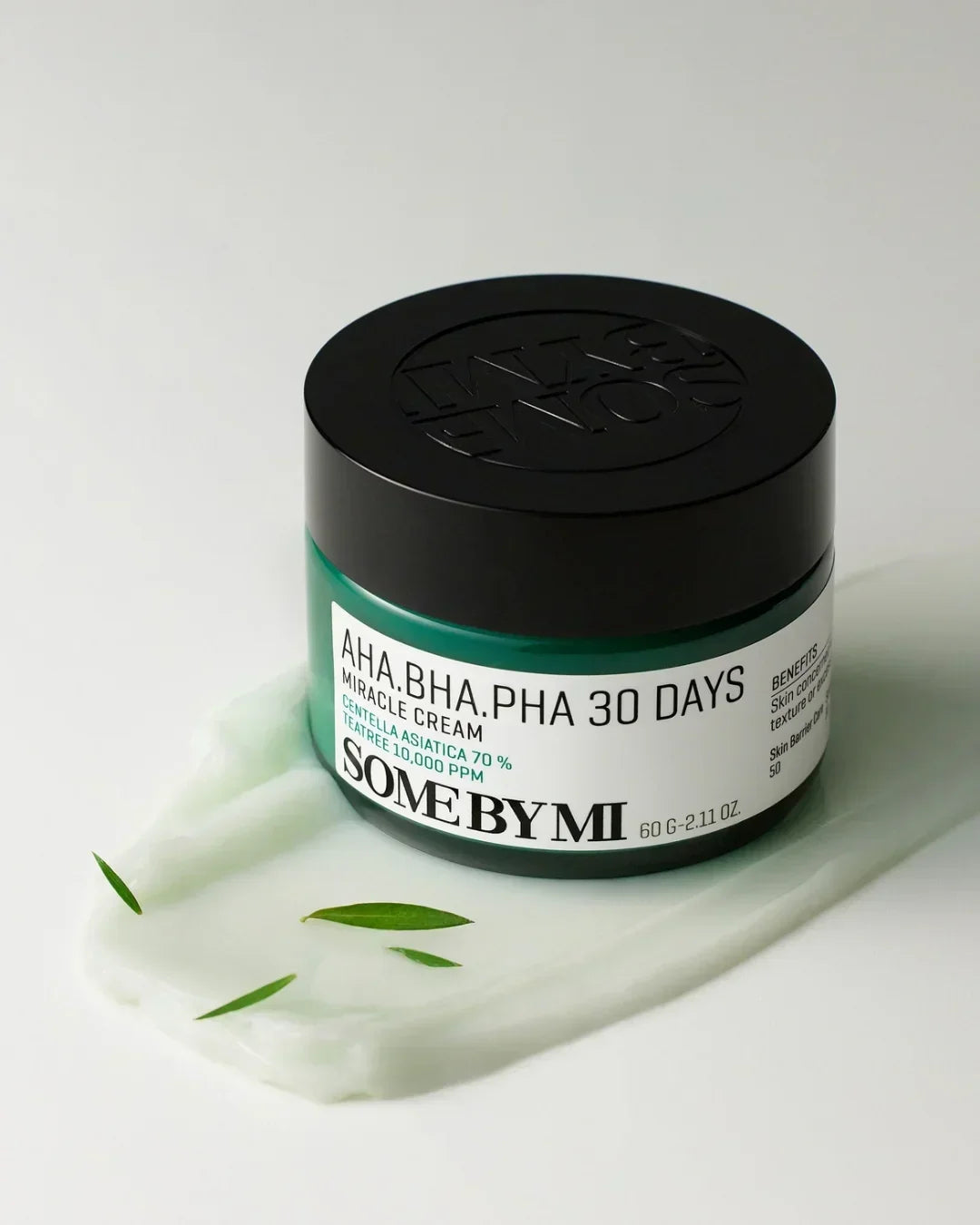 Some By Mi AHA BHA PHA 30 Days Miracle Cream jar on white surface with cream and green leaves