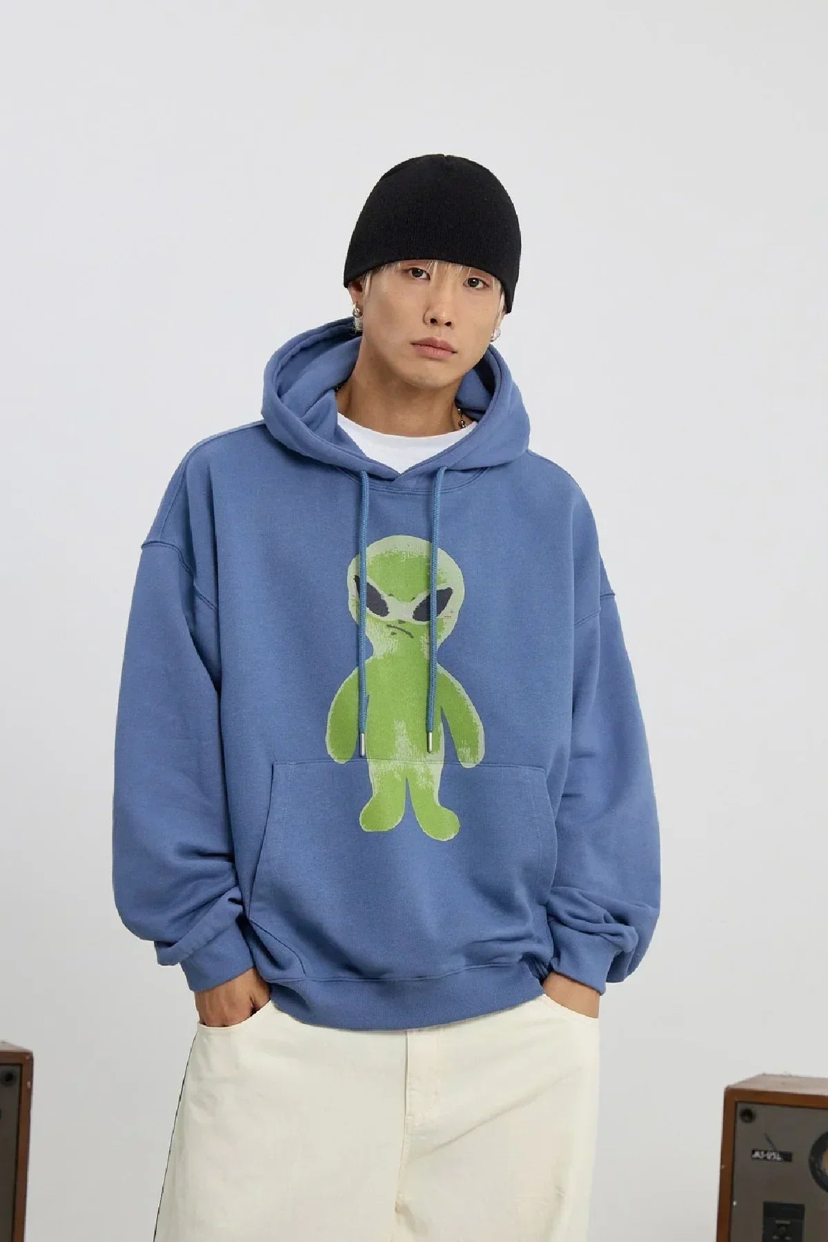 Man wearing dust blue hoodie with green alien graphic and black beanie