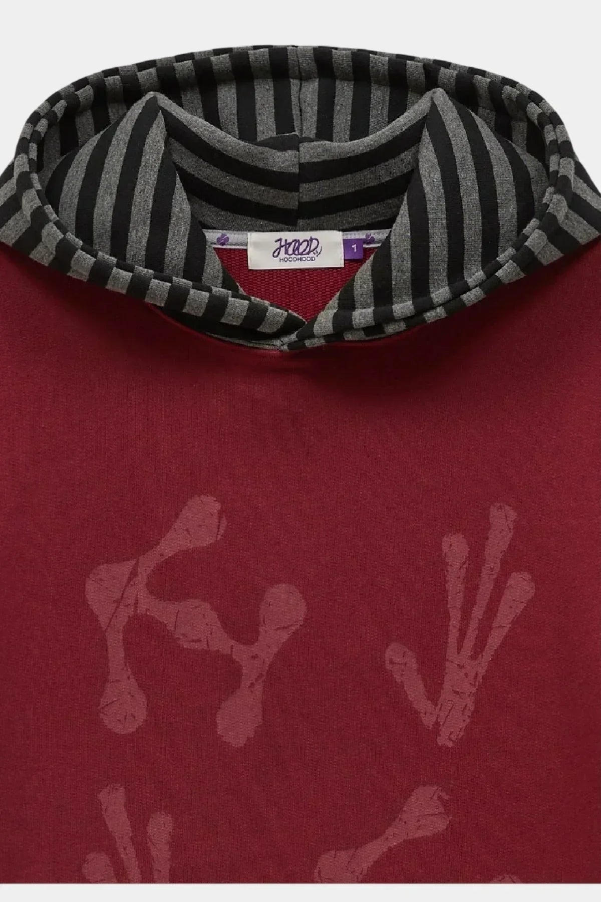 Close-up of burgundy hoodie with black and gray striped hood and subtle alien hand print detail