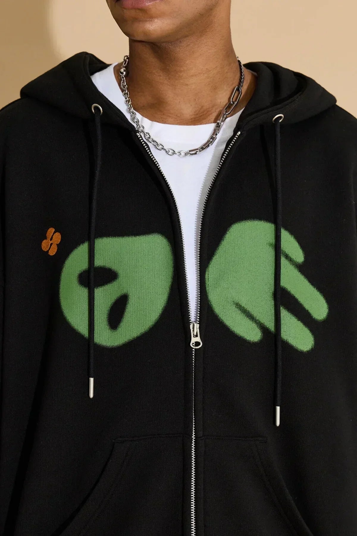 Close-up of black zip-up hoodie with green alien hands graphic and silver chain necklace