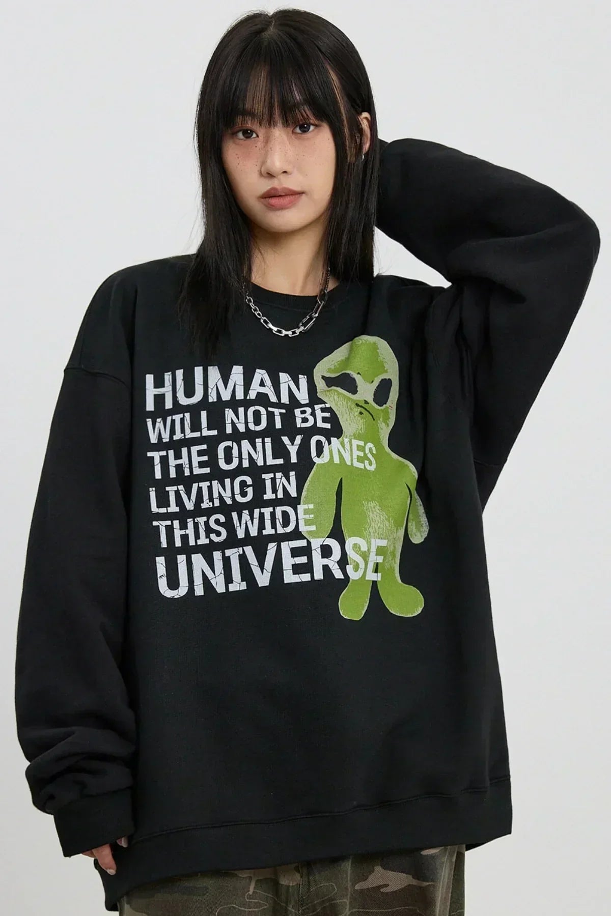 Woman wearing black sweatshirt with green alien and text about humans not being the only life in the universe