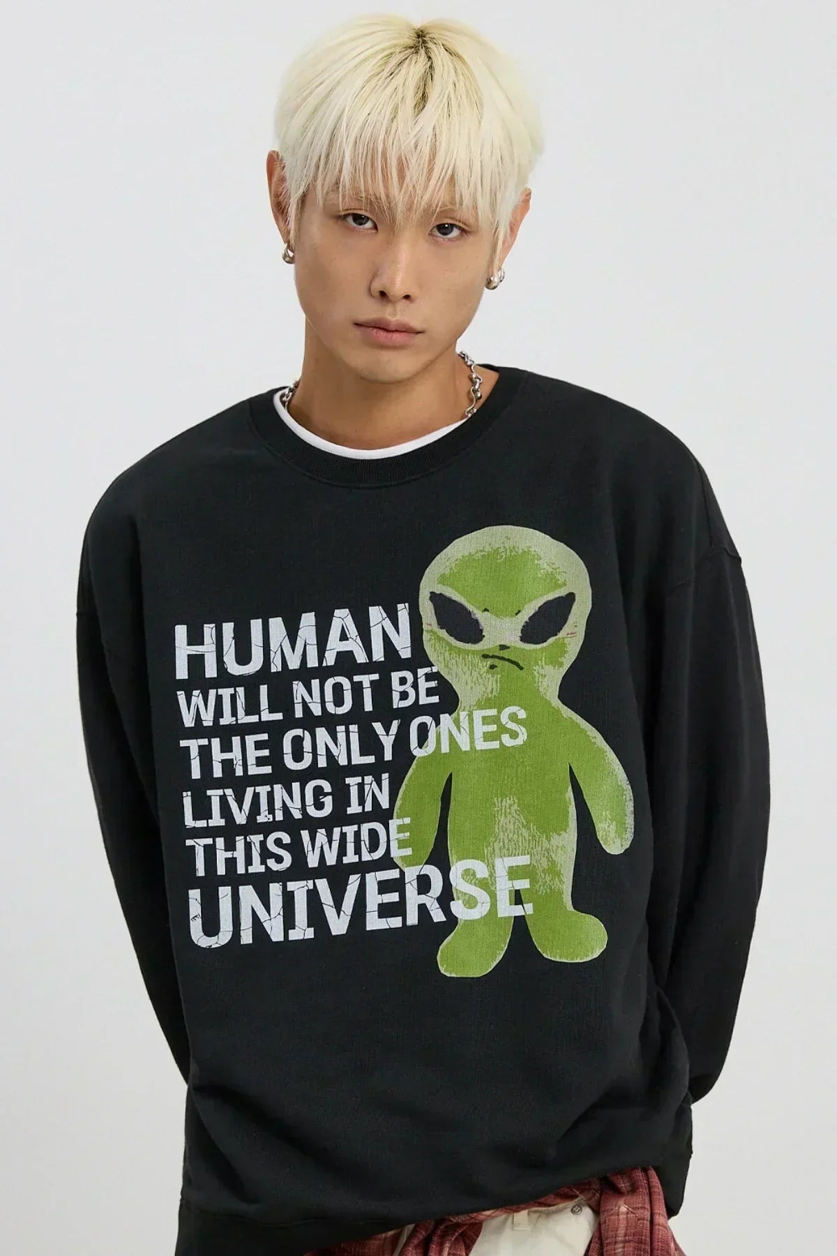 Person wearing black sweatshirt with green alien and white slogan about humans in the universe