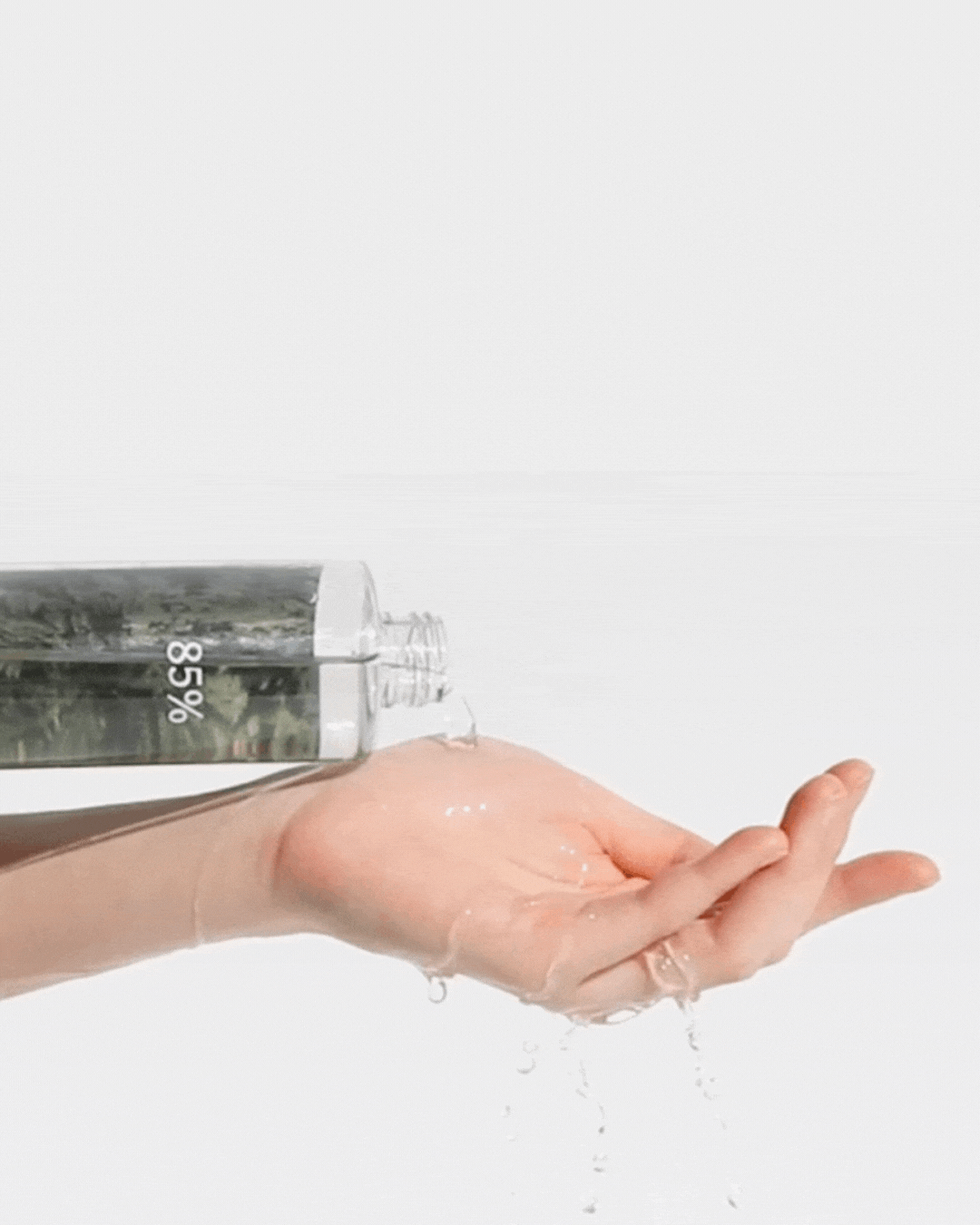 Hand pouring clear Anastatica skin conditioning toner liquid from bottle labeled 85% on plain white background