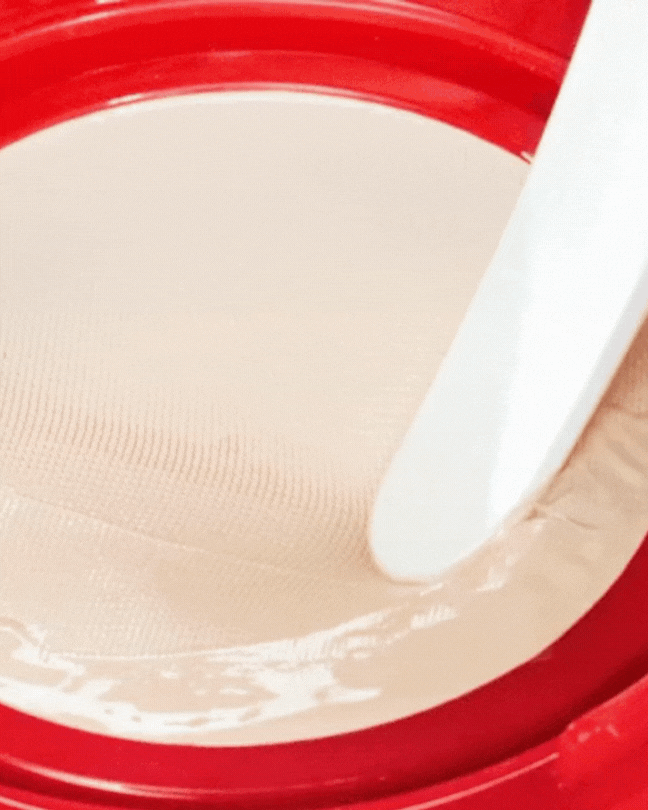 Close-up of Apple Dewy Fit Cushion makeup with smooth beige texture in red compact