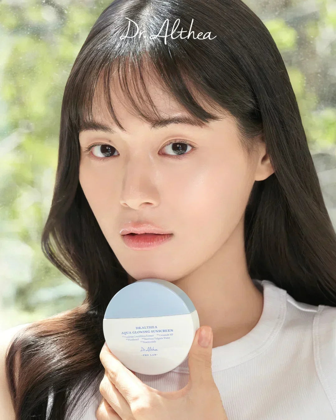 Woman holding Dr. Althea Aqua Glowing Sunscreen 45ml with natural glowing skin in bright setting