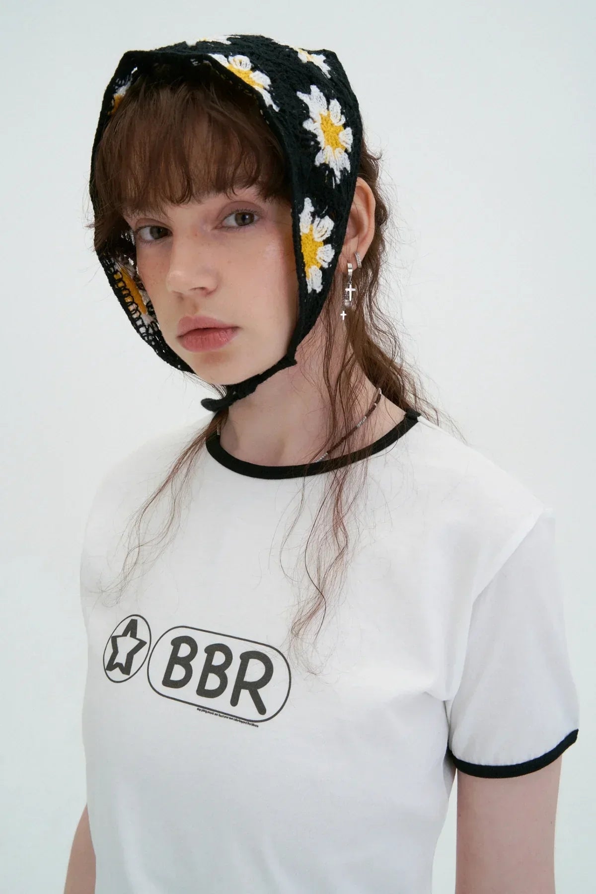 Young woman wearing white BBR logo t-shirt and black crochet bonnet with white and yellow daisies