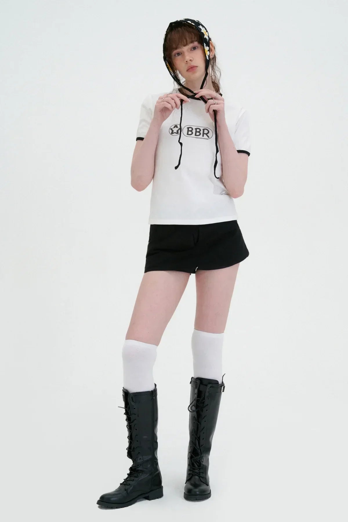 Model in white BBR logo tee, black shorts, knee-high white socks, black boots, and floral headscarf