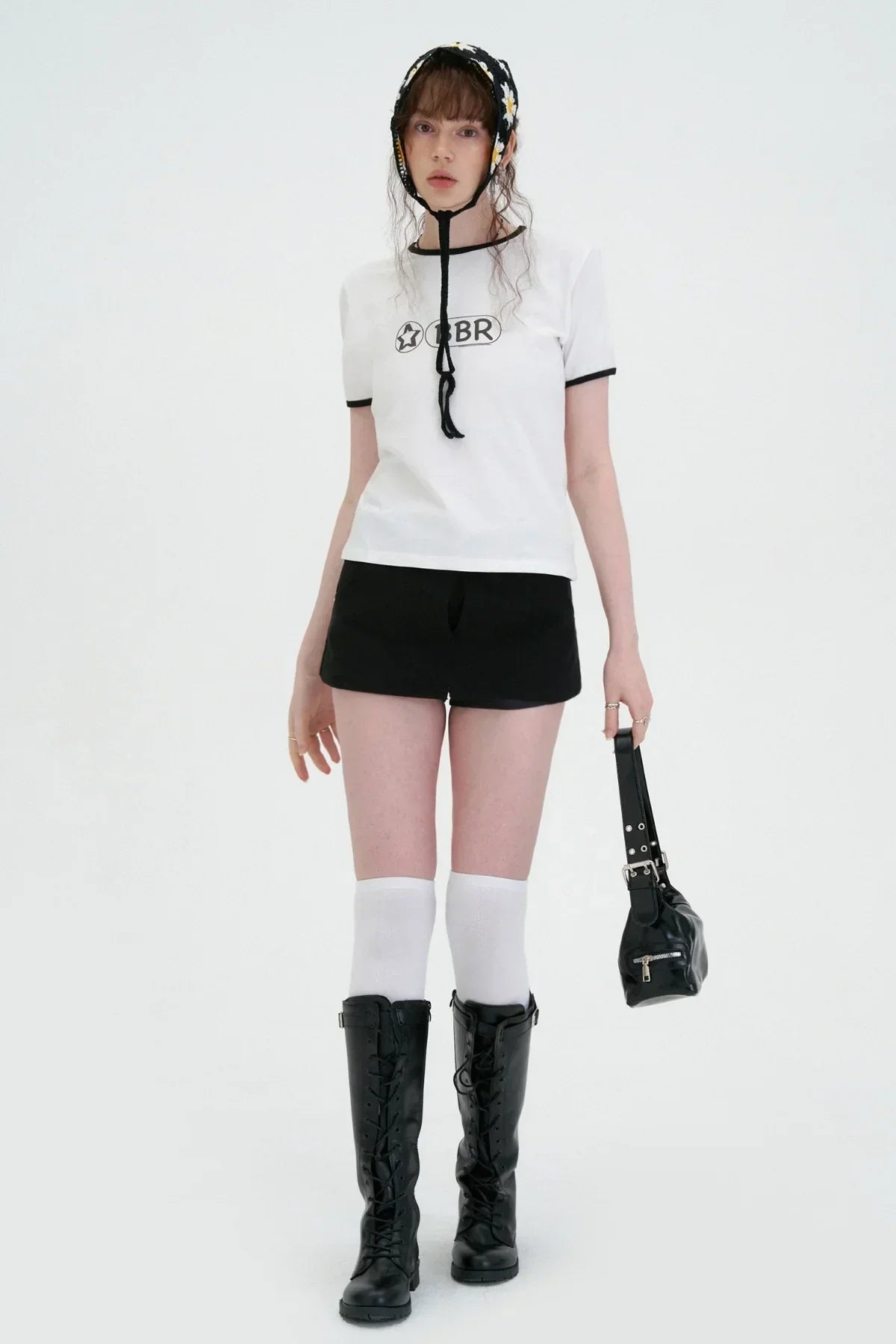 Model wearing white BBR logo t-shirt, black shorts, knee-high white socks, black boots, and floral bonnet