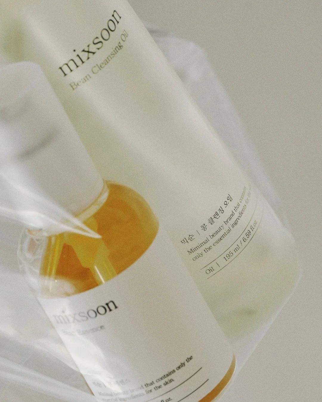 Mixsoon Bean Cleansing Oil 195ml bottle and a smaller clear bottle on a beige background