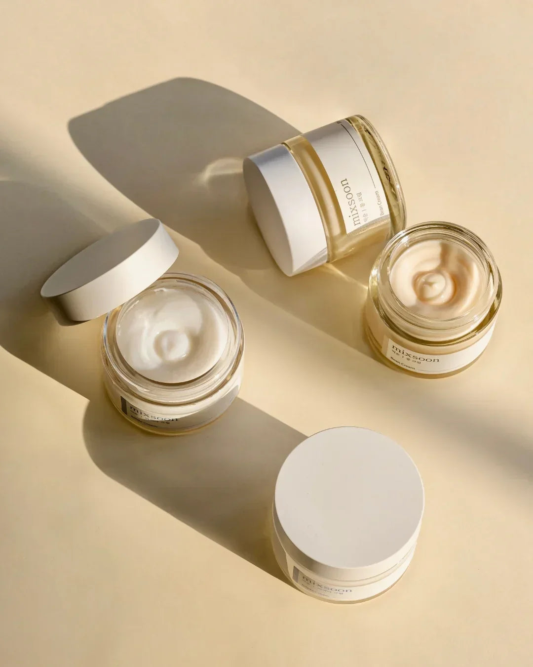 Mixsoon bean cream jars with white lids on beige surface in natural sunlight