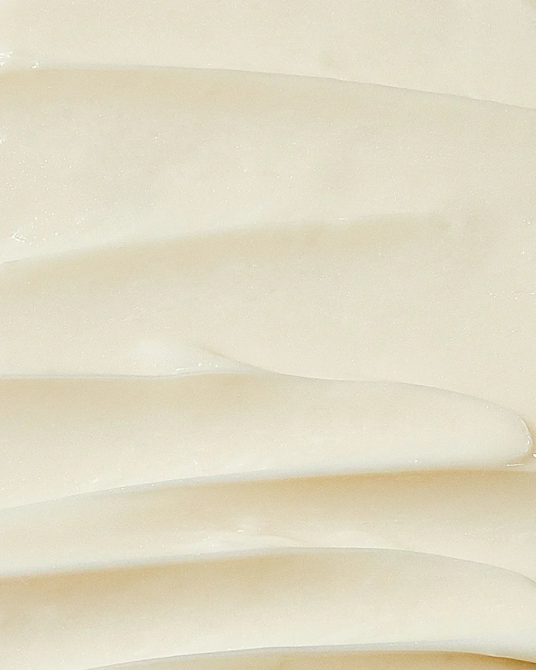 Smooth creamy beige skincare cream texture with soft streaks and glossy finish