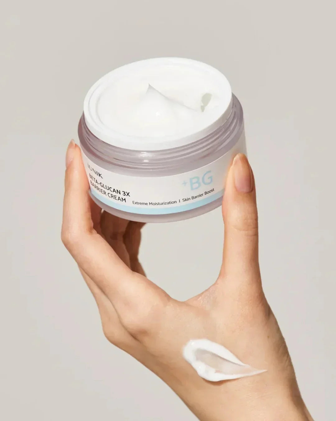 Hand holding iUNIK Beta-Glucan 3X Barrier Cream jar with cream on hand for moisturizing skin