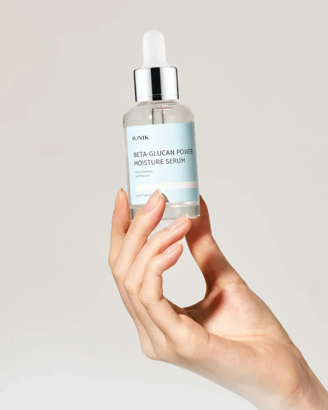 Hand holding a 50ml bottle of iUNIK Beta-Glucan Power Moisture Serum with dropper