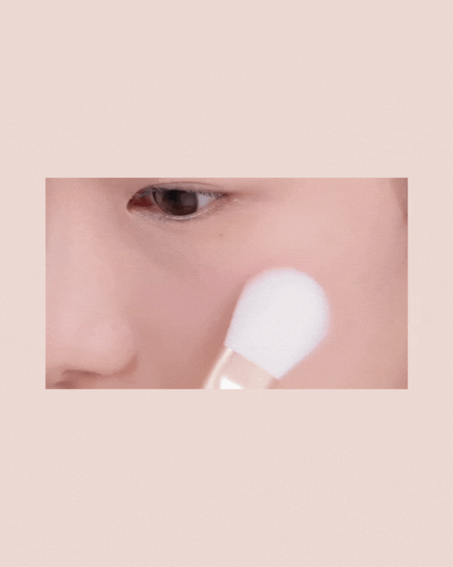 Close-up of person applying blush with a soft white makeup brush on cheek