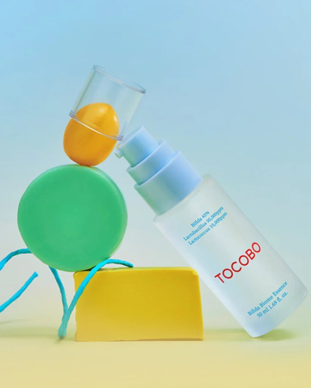 Tocobo Bifida Biome Essence 50ml bottle balancing on colorful geometric shapes with blue background