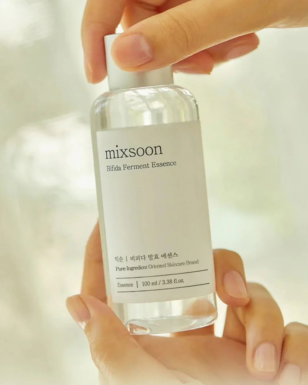 Hand holding Mixsoon Bifida Ferment Essence skincare bottle with clear design and white label