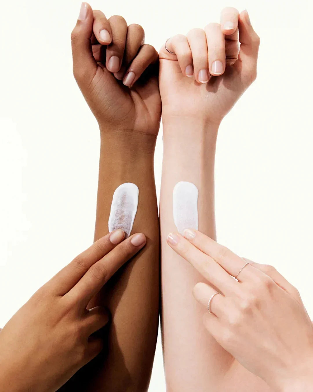 Two diverse arms with white sunscreen cream applied, demonstrating sun protection skincare