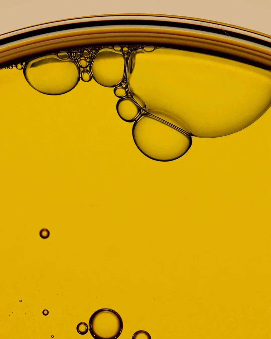 Close-up of golden yellow cleansing oil with visible air bubbles in liquid texture