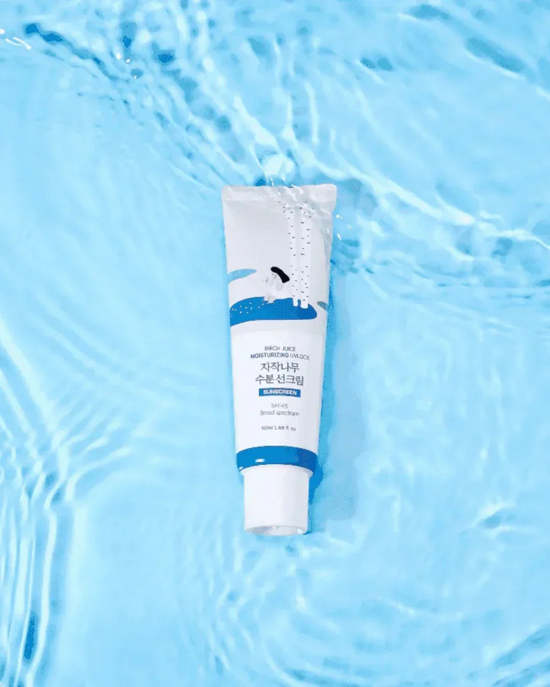 Birch juice moisturizing sunscreen SPF45 tube floating in clear blue water with ripple effect