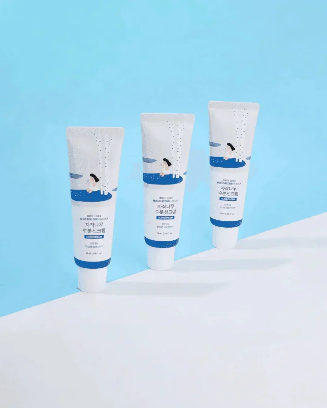 Three tubes of birch juice moisturizing sun cream with SPF 45 on a white and blue background