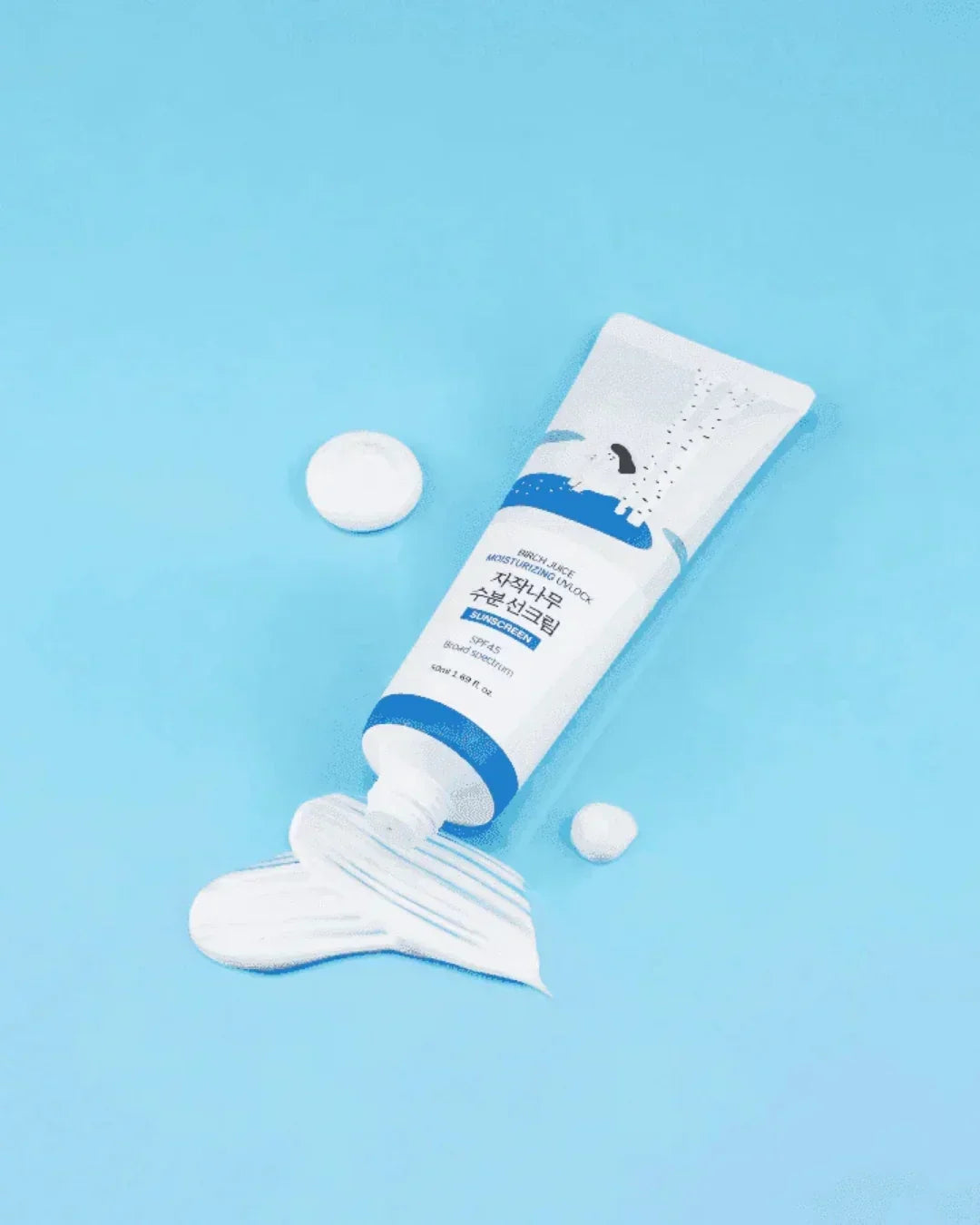 Tube of Birch Juice Moisturizing Sun Cream with SPF 45 and white cream texture on blue background