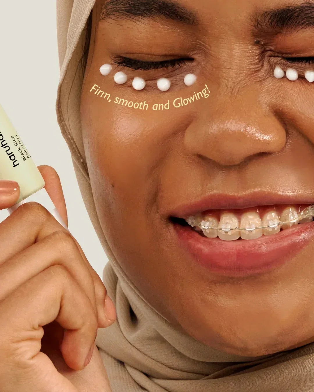 Close-up of smiling woman with braces applying Black Rice Bakuchiol eye cream with cream dots under her eyes