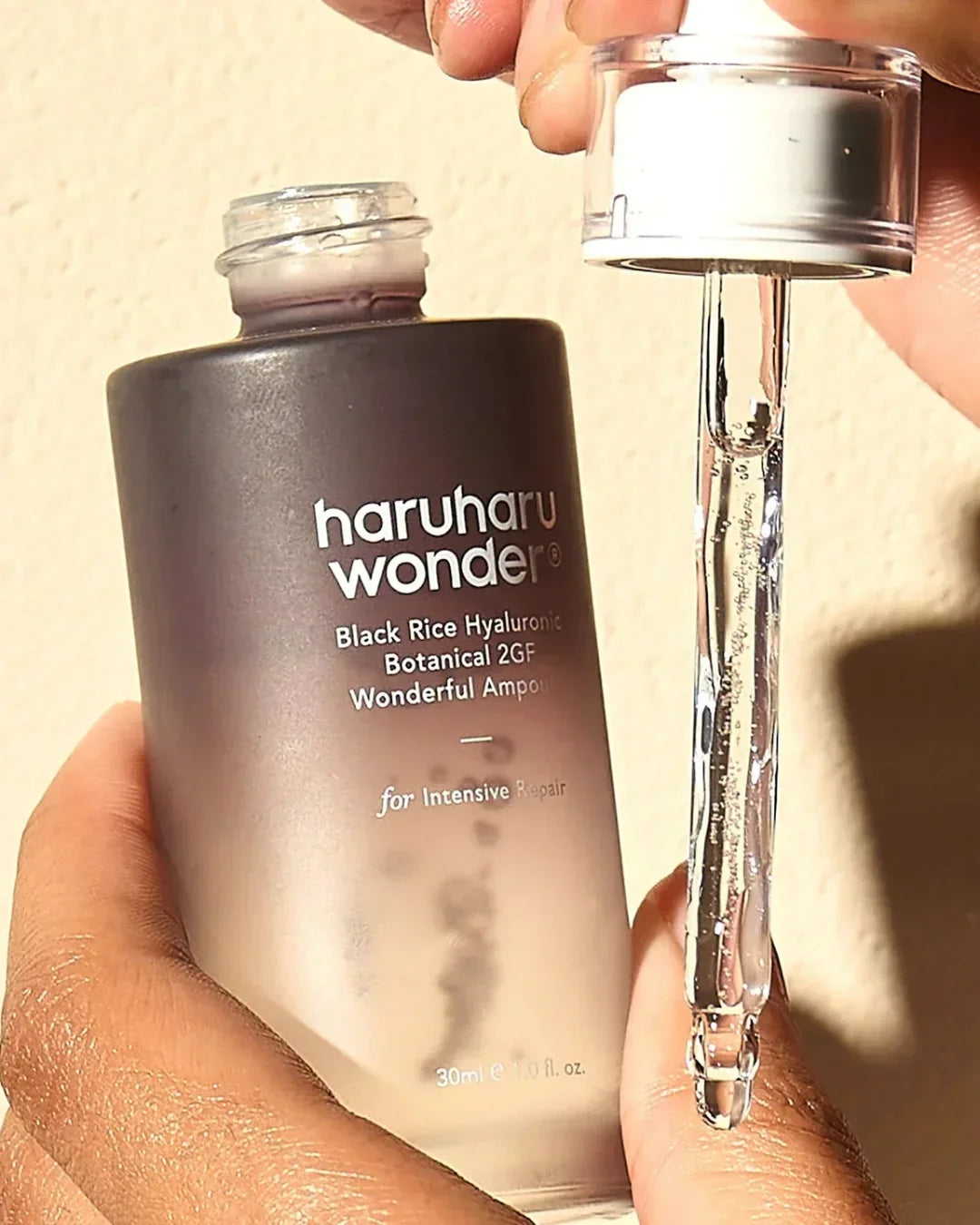 Hand holding Haruharu Wonder Black Rice Hyaluronic Botanical 2GF ampoule bottle and dropper