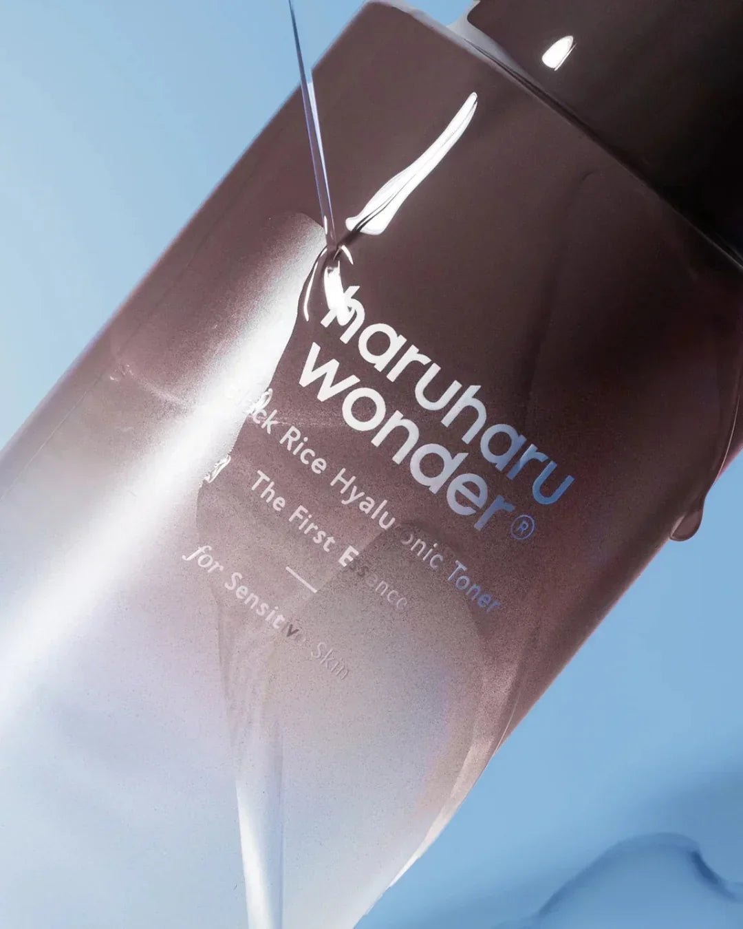 Maruharu Wonder Black Rice Hyaluronic Toner bottle for sensitive skin with liquid pouring on blue background