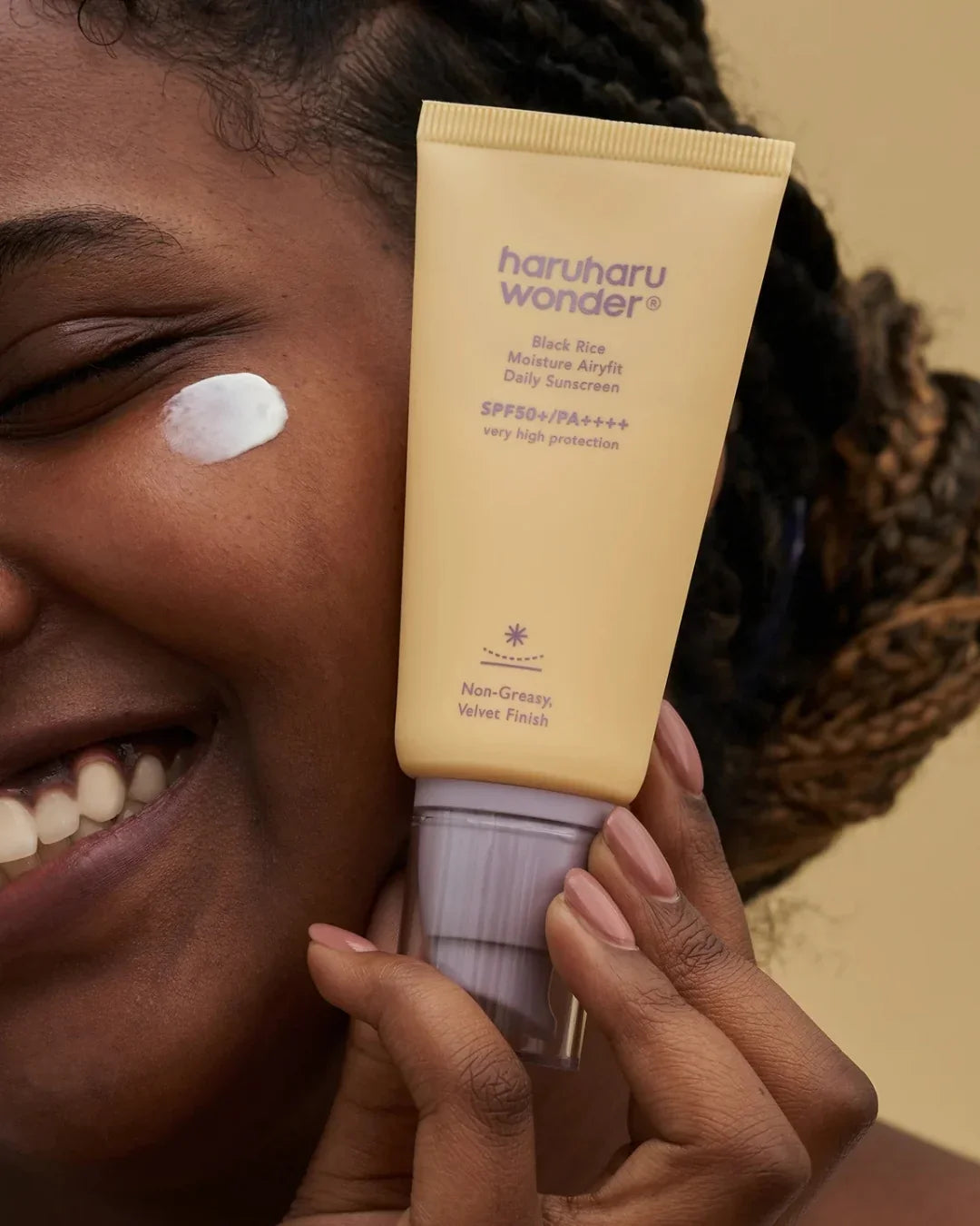 Smiling woman applies Haruharu Wonder Black Rice Moisture Airyfit Daily Sunscreen SPF50, Korean skincare