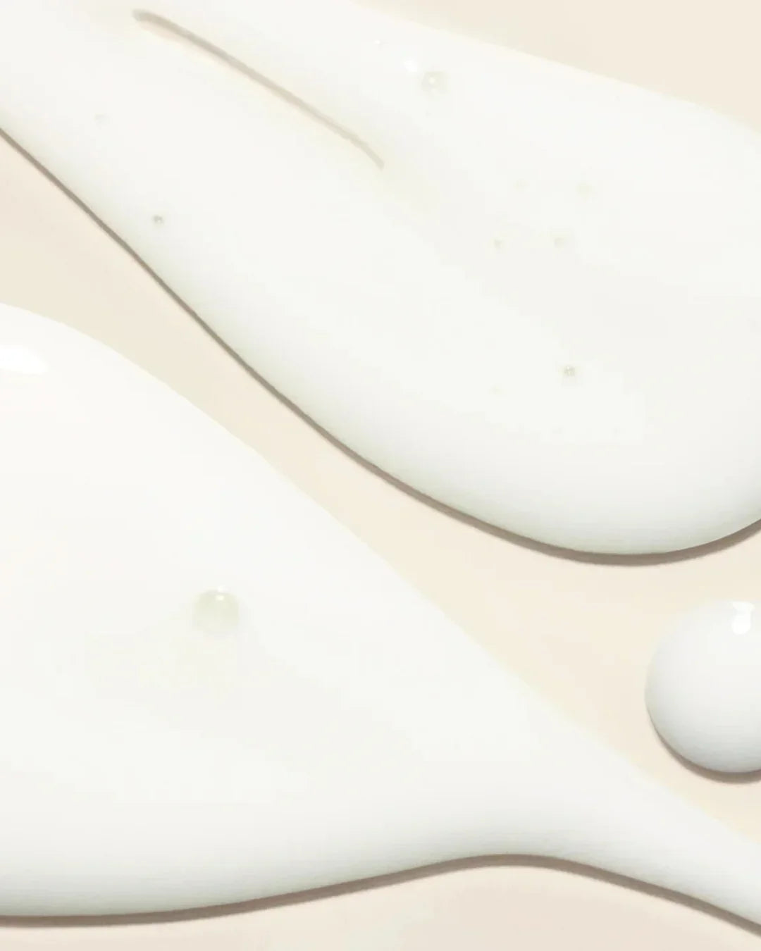 Close-up of smooth white retinol serum texture with glossy droplets on beige background