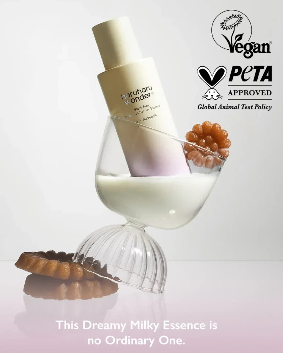 HaruHaru Wonder Black Rice Probiotics Barrier Essence in tilted glass with creamy liquid and brown flower-shaped items, vegan and PETA approved