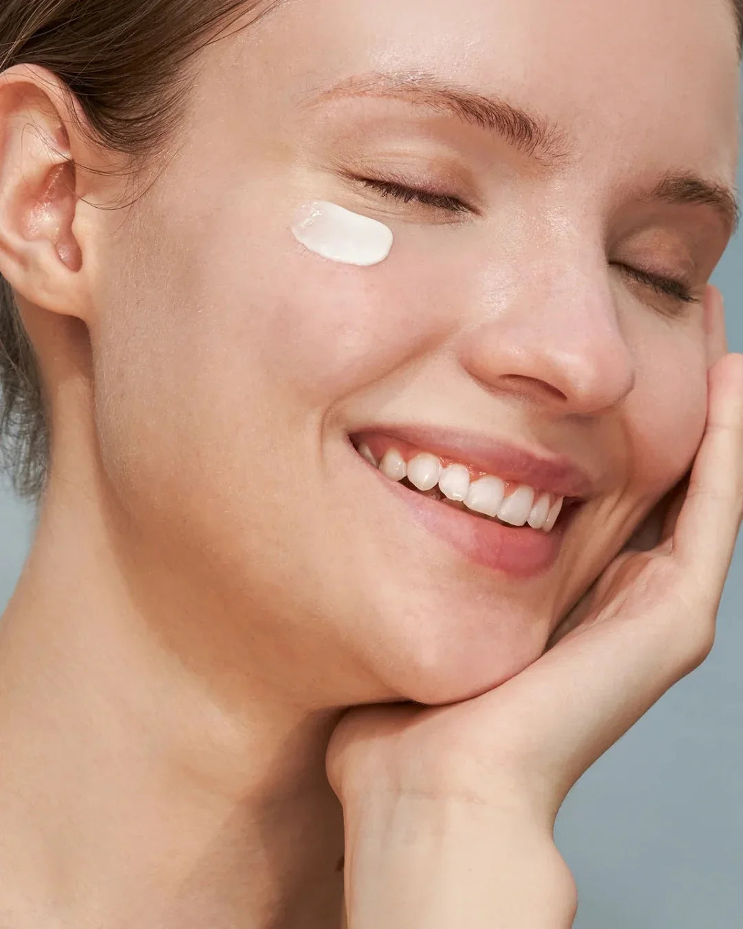 Smiling woman applying Korean mineral sunscreen, Malkn skincare, glowing complexion
