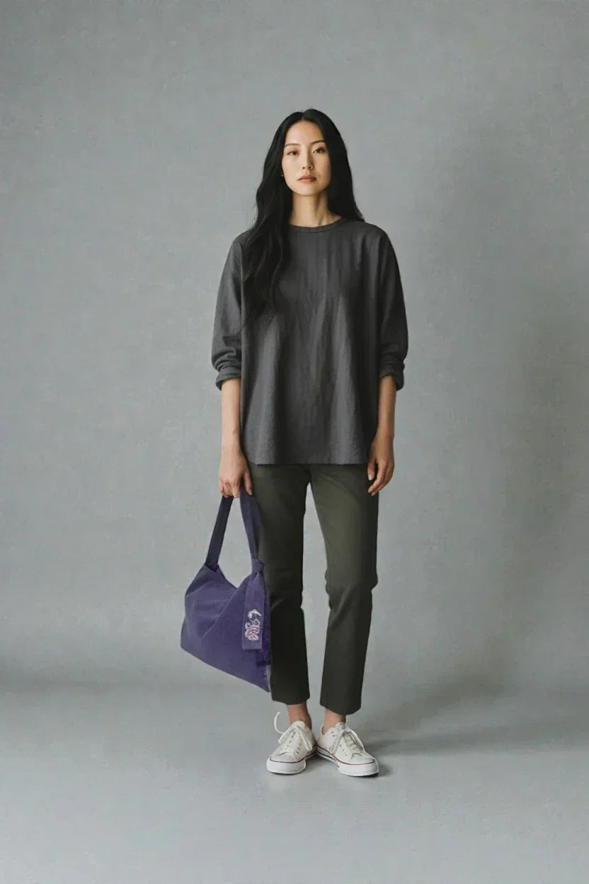Woman in casual dark gray top and green pants holding purple butterfly daily bag with embroidery